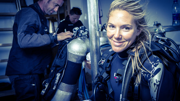 Divers preparing their equipment while wearing exposure suits